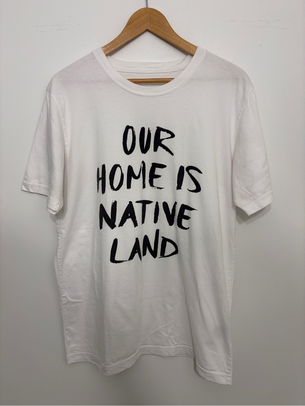 White Graphic Tee with Black Text - "Our Home Is Native Land"